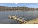 A wooden dock extends onto a tranquil lake, surrounded by a landscape of trees, offering serene waterfront access at 459 Lester Rd, Fayetteville, GA 30215