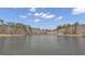 Scenic view of a wide, calm lake surrounded by a dense forest of trees against a blue sky with scattered clouds at 459 Lester Rd, Fayetteville, GA 30215