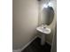 Cozy half bath featuring a pedestal sink, oval mirror, and warm lighting at 5425 Twin Lakes Dr, Atlanta, GA 30349