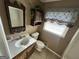 Bathroom with a white sink, toilet, and decorative accents, with a window for natural light at 160 Appalachee Church Rd, Auburn, GA 30011
