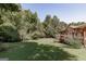 A large, grassy backyard surrounded by mature trees with a view of the home's rear exterior and wooden deck at 2278 Honeysuckle Se Ln, Smyrna, GA 30080