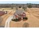 Aerial view of a brick and stone home with a large yard, a circular driveway, and mature trees, offering privacy and space at 70 Caseys Way, Covington, GA 30014