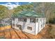 Two-story home with light siding, dark shutters, and a green roof, set in a wooded area at 6274 Booker Ln, Lithonia, GA 30058