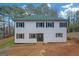 Two-story home with light siding, dark shutters, and a green roof, set in a wooded area at 6274 Booker Ln, Lithonia, GA 30058