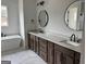 Modern bathroom featuring double vanity with stone countertop, dual mirrors, and a freestanding tub at 130 Dockside Dr # 380, Fayetteville, GA 30215