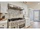 Modern kitchen with a large stove, stainless steel hood, and herringbone tile backsplash at 25 Grange Way, Sharpsburg, GA 30277