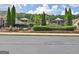 View of a community outdoor lounge area with mature landscaping, a stone retaining wall, and a black iron fence at 430 Rehobeth Way, Fayetteville, GA 30214