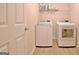 Functional laundry room with white washer and dryer, plus storage shelf at 430 Rehobeth Way, Fayetteville, GA 30214