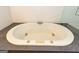 Close-up of a modern white soaking tub surrounded by stone tile, offering a luxurious bathing experience at 155 Glenwood Ln, Fayetteville, GA 30215