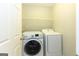 Bright laundry room featuring a white washer and dryer, plus convenient overhead shelving for storage at 155 Glenwood Ln, Fayetteville, GA 30215