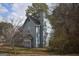 Side view of a blue two-story home shows mature trees, a well-maintained lawn, and architectural details, creating a peaceful setting at 3281 Nina Way, Douglasville, GA 30135