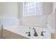 Close-up of soaking tub with tile surround and frosted glass block window at 243 Long Dr, Mcdonough, GA 30253