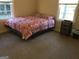 Bedroom with neutral walls and carpet, and a colorful patterned comforter at 2421 Rockbridge Sw Rd, Stone Mountain, GA 30087