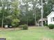 Spacious front yard with mature trees, landscaping, and a carport, offering ample parking at 2421 Rockbridge Sw Rd, Stone Mountain, GA 30087