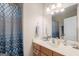 Bathroom with patterned shower curtain, wood vanity, and large mirror at 101 Kenmare Row, Tyrone, GA 30290