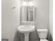 Powder room with white pedestal sink, toilet, and simple mirror at 101 Kenmare Row, Tyrone, GA 30290
