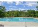 Full swimming pool surrounded by trees in a park-like community on a partly cloudy day at 101 Kenmare Row, Tyrone, GA 30290