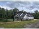 Sprawling white farmhouse with a black fence and green trees in the background at Lot C Montannas Way, Moreland, GA 30259