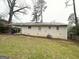 Exterior of the home with a grassy backyard, large trees, and small windows at 2634 Rockcliff Se Rd, Atlanta, GA 30316