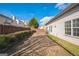A backyard with a brick patio, hedges, and a wooden fence under a partly cloudy blue sky at 7764 Parkside Dr, Lithia Springs, GA 30122