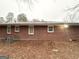 View of the home's exterior brick wall, windows, and backyard covered in leaves at 648 Ozburn Nw Rd, Atlanta, GA 30318