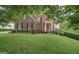 Charming two-story brick home with a red front door and well-manicured lawn, surrounded by mature trees in a lush neighborhood at 6410 E Hills Ct, Cumming, GA 30041