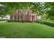 Charming two-story brick home with a red front door and well-manicured lawn, surrounded by mature trees in a lush neighborhood at 6410 E Hills Ct, Cumming, GA 30041