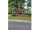 Charming two-story brick home with a red front door and well-manicured lawn, surrounded by mature trees in a lush neighborhood at 6410 E Hills Ct, Cumming, GA 30041