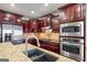 Gourmet kitchen with stainless steel appliances, granite counters, cherry cabinets, and tile backsplash is perfect for entertaining at 50 Red River Ct, Covington, GA 30014