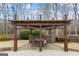 Exterior pergola with brick base, concrete floor, and wood roof with outdoor table and chairs at 50 Red River Ct, Covington, GA 30014
