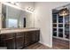 This primary bathroom features double sinks, dark wood cabinets, and leads into a spacious walk-in closet at 121 Amelia Way, Ellenwood, GA 30294