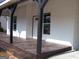 A porch view with dark wooden support beams, a stained concrete floor, and brick pavers at 917 Jackson St, Locust Grove, GA 30248