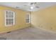 Sunny bedroom with yellow walls features carpet, a ceiling fan, and natural light from two windows at 445 Turner Dr, Mcdonough, GA 30252