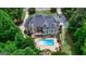 Aerial of a backyard featuring a sparkling pool, patio, tiered deck, and lush landscaping, mature trees at 709 Prestige Pt, Peachtree City, GA 30269