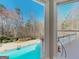 View from a window of a backyard with a swimming pool, mature trees, and patio furniture at 709 Prestige Pt, Peachtree City, GA 30269