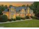 Expansive facade showing stone and stucco, arched windows, and manicured landscaping. Exterior lights add warmth at 709 Prestige Pt, Peachtree City, GA 30269