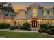 Exterior view of a stone accented home, double front doors, manicured shrubs, and sunset background at 709 Prestige Pt, Peachtree City, GA 30269
