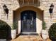 Elegant stone entryway featuring an arched doorway with iron double doors and sconce lighting at 709 Prestige Pt, Peachtree City, GA 30269