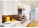 Gourmet kitchen with stainless steel appliances, white cabinets, and tiled backsplash at 709 Prestige Pt, Peachtree City, GA 30269