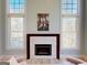 Living room with fireplace featuring white stone and dark wood mantel, with large windows at 709 Prestige Pt, Peachtree City, GA 30269
