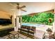 A lovely covered outdoor patio with a fan and television facing a pool and lush greenery at 709 Prestige Pt, Peachtree City, GA 30269