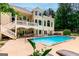 Back of house with a large pool and patio with lounge chairs and beautiful manicured shrubs at 709 Prestige Pt, Peachtree City, GA 30269