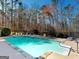 An inviting backyard pool with a lounge area surrounded by lush greenery creating a private oasis at 709 Prestige Pt, Peachtree City, GA 30269