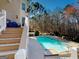 A view of the pool from the outdoor stairs of the home's exterior, showcasing a wooded backdrop at 709 Prestige Pt, Peachtree City, GA 30269