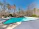 A stunning backyard pool surrounded by a concrete patio and views of the lush landscaping at 709 Prestige Pt, Peachtree City, GA 30269
