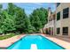 Backyard view with a large in-ground pool with diving board surrounded by lush landscaping at 709 Prestige Pt, Peachtree City, GA 30269