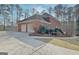 Side view of brick home showing the three car garage, driveway, and mature landscaping at 185 Lady Helen Ct, Fayetteville, GA 30214