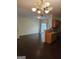 Open living room featuring dark wood floors, a chandelier, and kitchen area with granite countertop at 2764 Keystone Ave, Lithonia, GA 30058