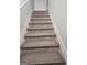 Carpeted staircase featuring white trim and handrail offers a seamless transition between floors in the home at 2764 Keystone Ave, Lithonia, GA 30058