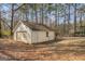 View of detached two car garage with faded green vegetation on roof and chain link fence at 787 N Ola Rd, Mcdonough, GA 30252